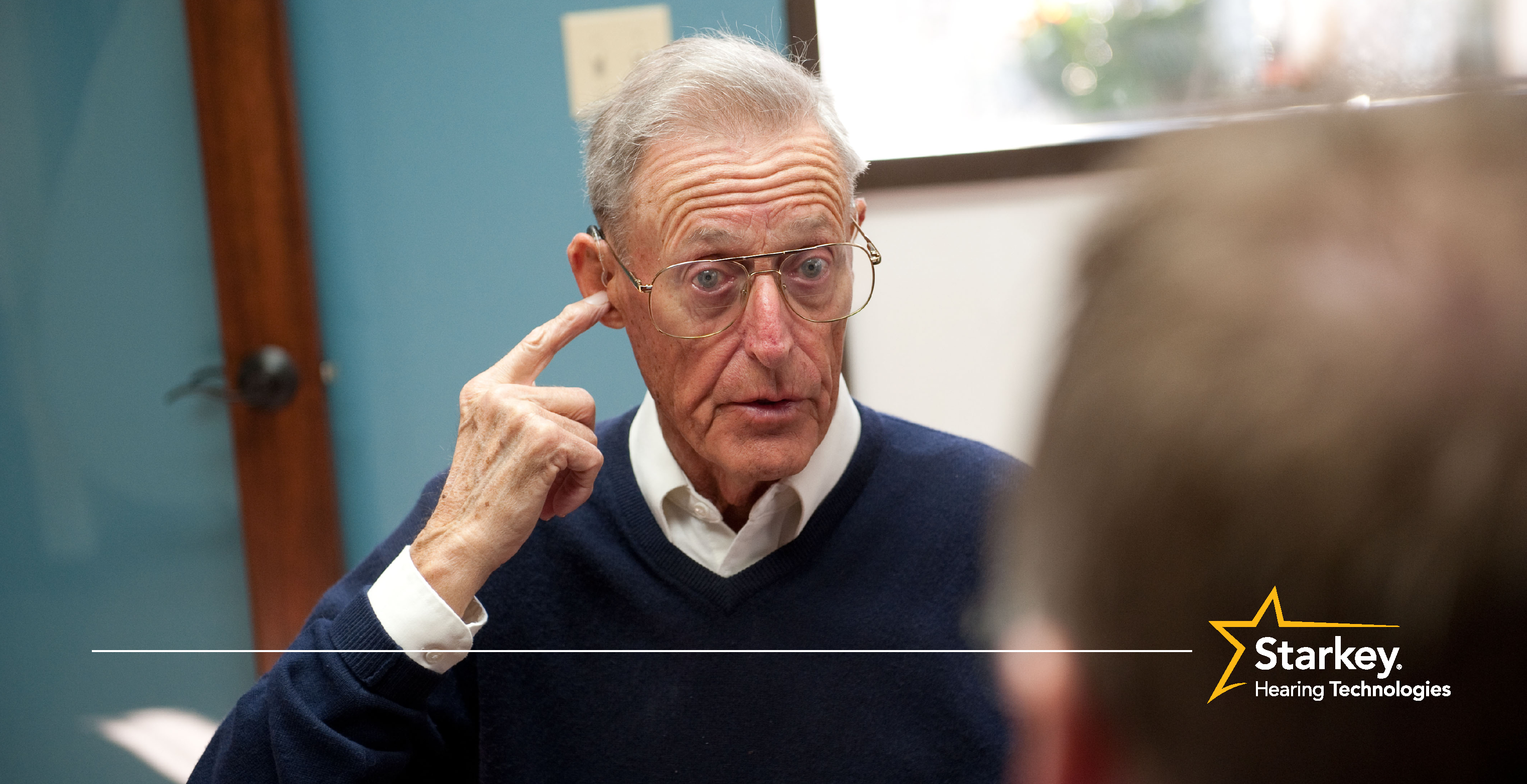 Homme plus âgé pointant son index sur son oreille droite